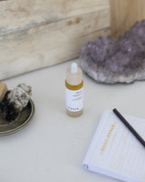 HENUA Miracle Vitamin Oil bottle on a serene setting with journaling pen and paper