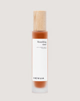 Henua beautifying toner bottle with a wooden cap on a beige background