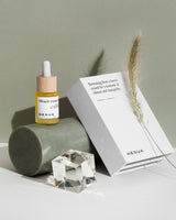 HENUA Miracle vitamin face oil with packaging and crystal on a neutral background