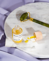 Henua skincare product with dropper and roller on a marble surface