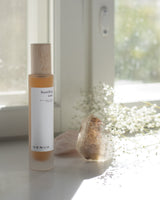 Henua skincare bottle on a white surface with a blurred natural background
