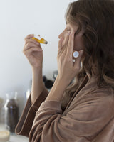 Woman applying Henua eye serum in a bathroom setting